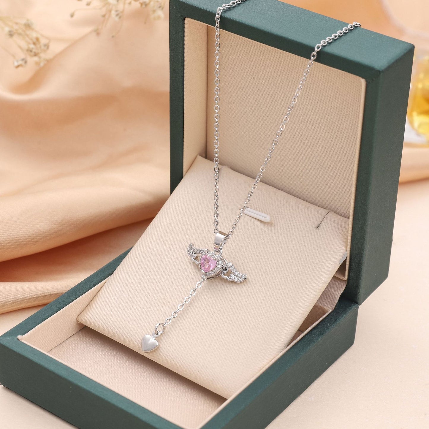 Amorital angel wings necklace with pink heart crystal — gold and silver pendant symbolizing love, luck, purity, and protection
